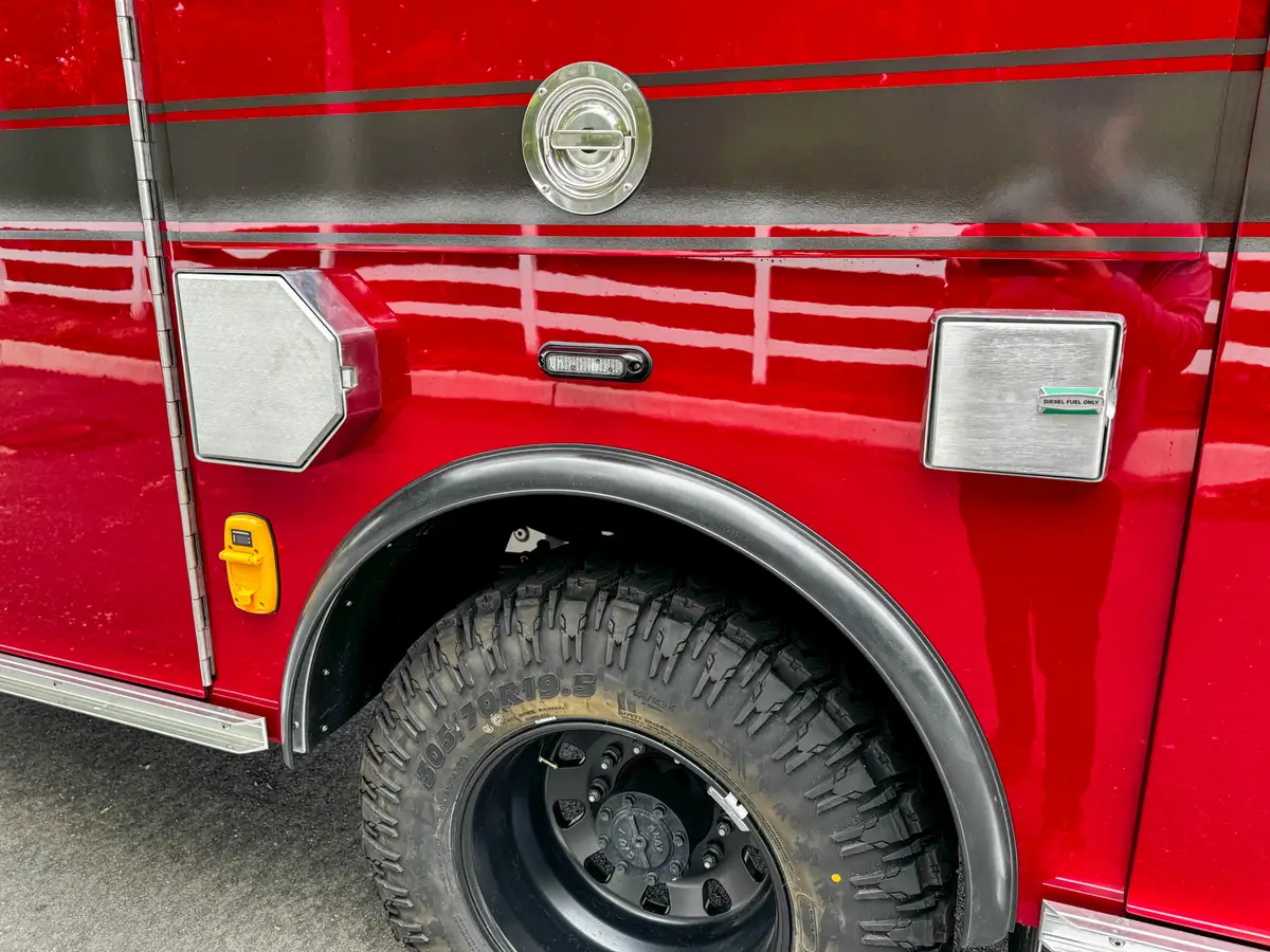 Open fuel-fill door close-up showing green fill cap above the rear wheel.